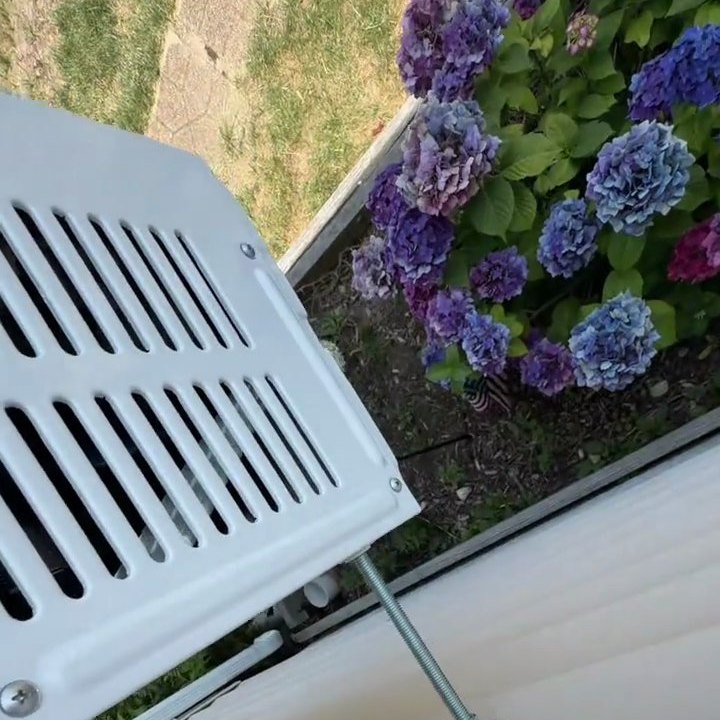 The compressor half hanging outside, below the window line